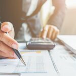 Gros plan sur une main avec un stylo qui fait de la comptabilité d'entreprise